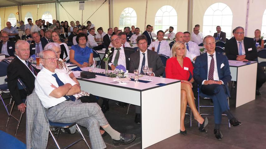 Mit der Einweihung ihres neuen Verwaltungsgebäudes am Hauptsitz in der Treuchtlinger Industriestraße bekannte sich die Firma Alfmeier nicht nur zu ihrem ländlichen Standort, sondern richtete den Blick mit ihrem „Technology Day“ zugleich weit darüber hinaus auf die gesamte Welt sowie den Wandel von Arbeit, Konsum und Gesellschaft im Zeitalter der Digitalisierung. Einen Einblick in die Arbeitsweise im Werk und den Labors gaben zwischen Festakt und Podiumsdiskussion zum Thema „Digitalisierung und die Auswirkungen auf die Arbeitswelt“ mehrere Rundgänge durch das Unternehmen. Dabei gab es auch schon einen Vorgeschmack auf die gerade entstehende „Smart Factory“ in Kooperation mit Siemens. Eine technische Spielerei, die zeigt was möglich ist, waren zwei Roboterarme, die Weißbier einschenkten. Für einen Schreckmoment sorgte das heftige Gewitter, das am späten Nachmittag kurzzeitig drohte, das Festzelt wegzublasen und unter Wasser zu setzen.