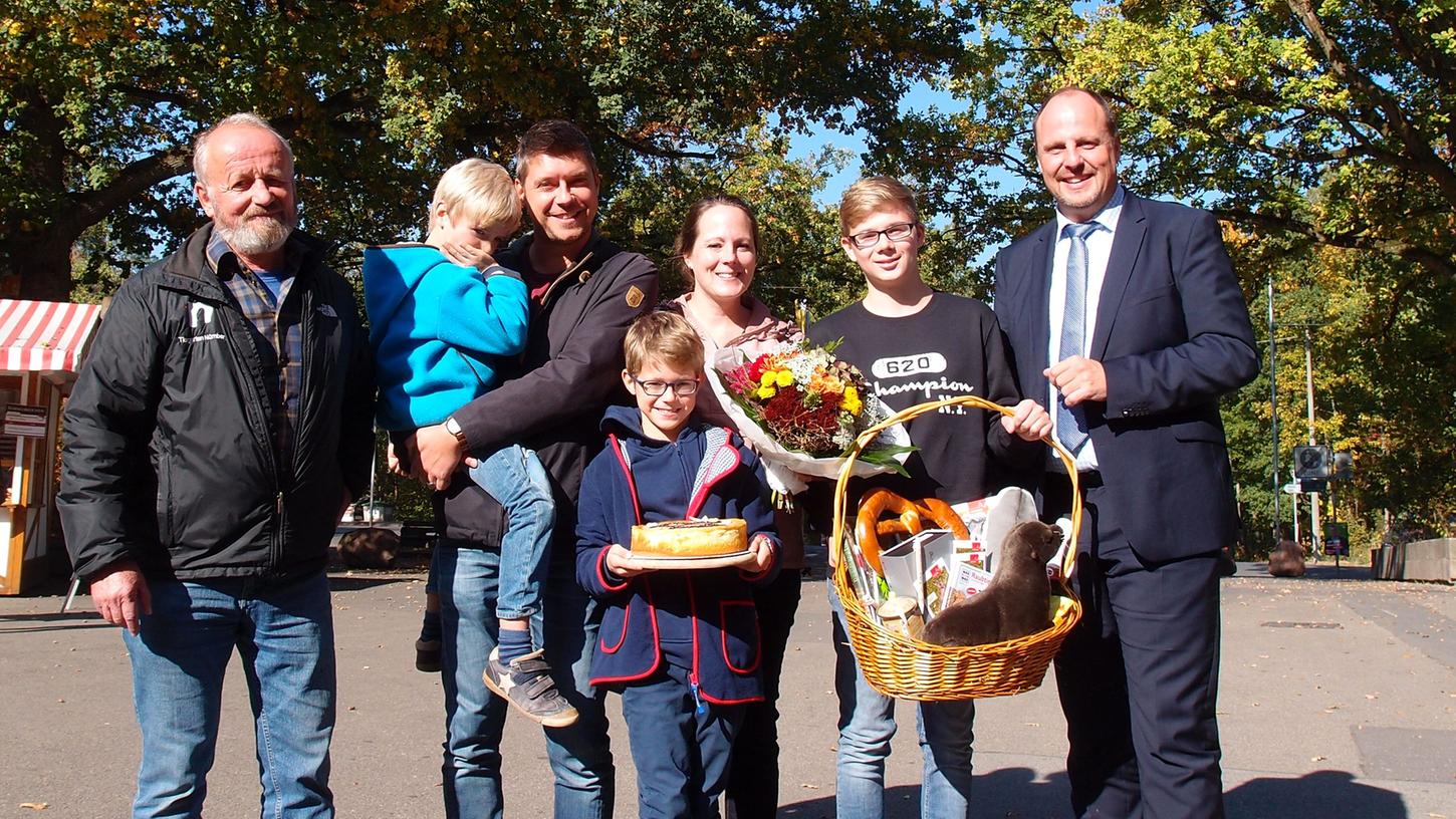 Familie Schmidt-Ullrich waren die millionsten Besucher des Tiergartens Nürnberg im Jahr 2018. Bürgermeister Christian Vogel (rechts) und Dr. Helmut Mägdefrau, stellv. Direktor des Tiergartens Nürnberg (links), überreichten einen Blumenstrauß, eine kleine Torte und einen üppig gefüllten Geschenkkorb.