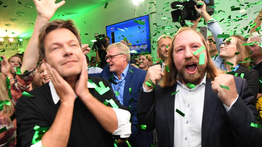Eine echte Wahlparty gibt es hingegen nur bei den Grünen. Fraktionsvorsitzender Anton Hofreiter (von rechts) und Bundesvorsitzender Robert Habeck jubeln nach Bekanntgabe der ersten Ergebnisse im Konfetti-Regen.