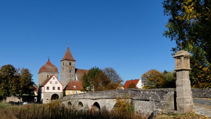 Die Altmühlbrücke in Ornbau vor strahlend blauem Himmel und herbstlichen Farben.