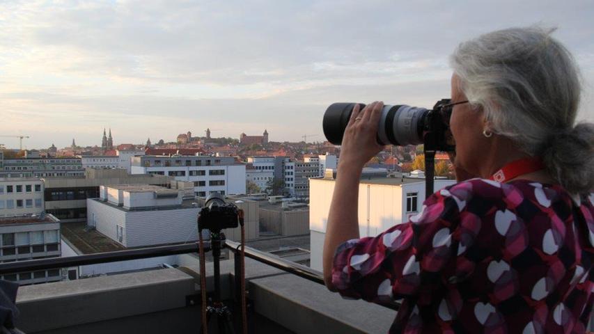 Des Teleobjektiv im Einsatz: Eine Fotografin fokussiert auf der Dachterrasse die Skyline der Altstadt.