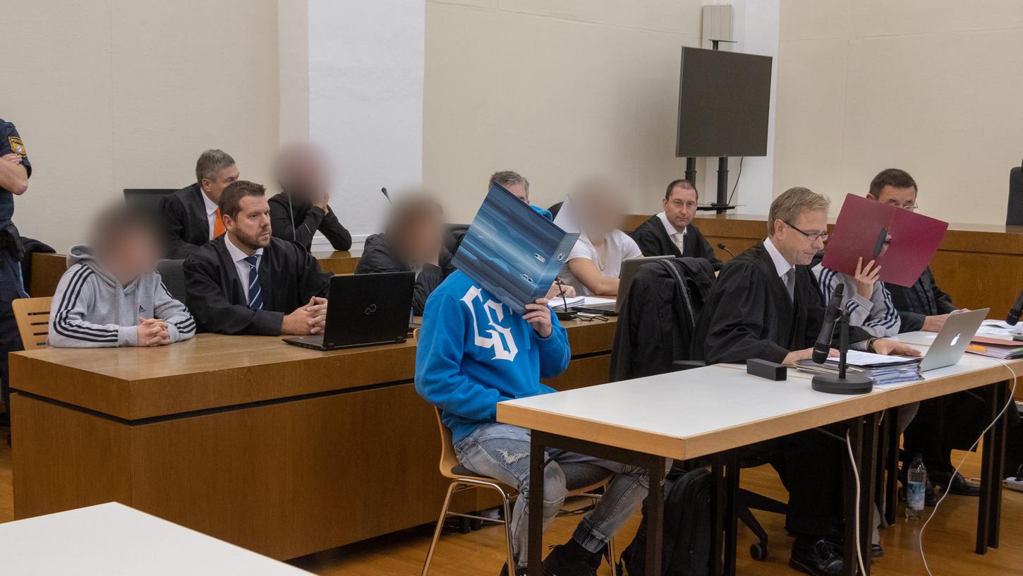 Die Angeklagten sitzen neben ihren Verteidigern im Verhandlungssaal im Passauer Landgericht.