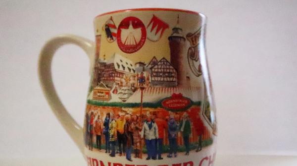 Die Tasse des Jahres 2018 war in den vergangenen Jahren wohl die Bunteste. In den darauffolgenden Jahren hielten sich die Designer mit den Farben eher zurück. 2018 hingegen zeigte das Motiv bunt gekleidete Besucherinnen und Besucher vor den Buden. Das Innere der Tasse erstrahlte - sofern nicht mit weißem oder rotem Glühwein gefüllt - in prächtigem Orange.