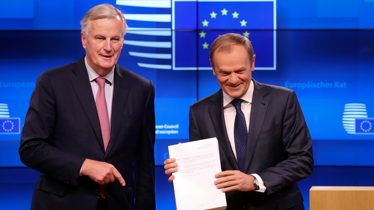 EU-Unterhändler Michel Barnier (l) übergibt den Entwurf des Austrittssabkommens zwischen Großbritannien und der EU an Donald Tusk, Präsident des Europäischen Rates, während einer Medienkonferenz im Europa-Gebäude.