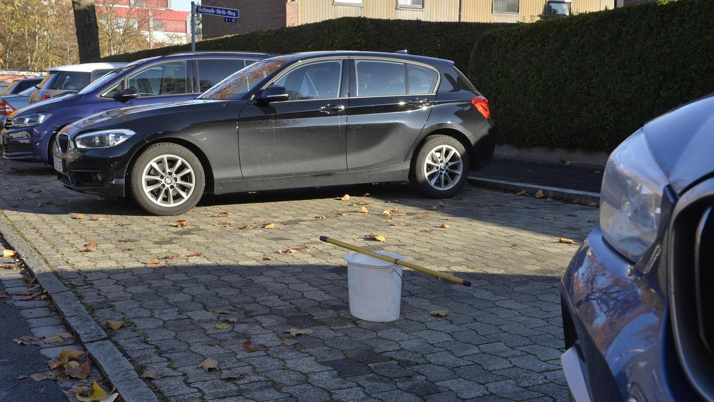 Mit Eimer und Besenstiel blockieren Anwohner am Helmut-Hirth-Weg Parkplätze vor ihrer Haustüre.
