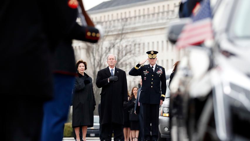 George W. Bush (M), ehemaliger Präsident der USA, und seine Frau Laura Bush (l) erweisen dem verstorbenen ehemaligen US-Präsidenten George H.W. Bush die Ehre, als dessen Sarg mit militärischen Ehren aus dem Kapitol getragen wird.