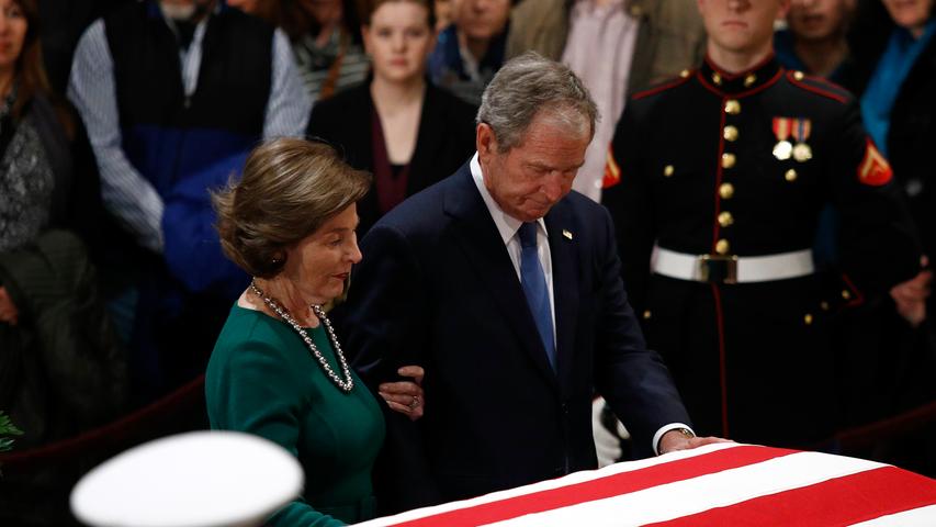 George W. Bush und seine Frau Laura halten vor dem Sarg inne.