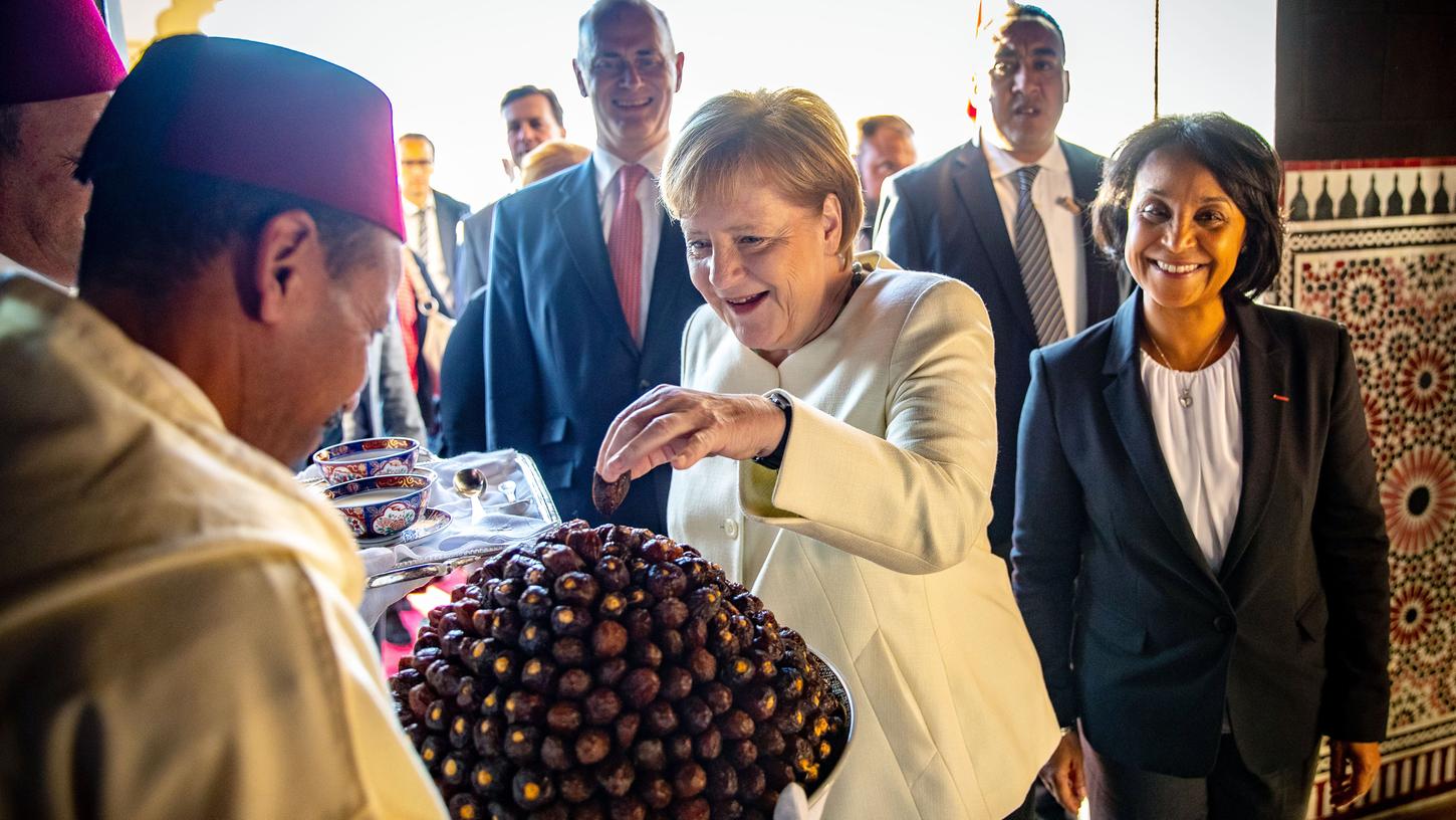 Angela Merkel (CDU) nimmt sich nach der Ankunft am Flughafen Marrakesch-Menara eine Dattel. Die Bundeskanzlerin befindet sich auf ihrer Reise zur UN-Konferenz zur Annahme des Migrationspaktes in Marokko. Unter dem Dach der Vereinten Nationen (UN) will die internationale Gemeinschaft einen weltweiten Vertrag zur sicheren, geordneten und regulären Migration verabschieden.