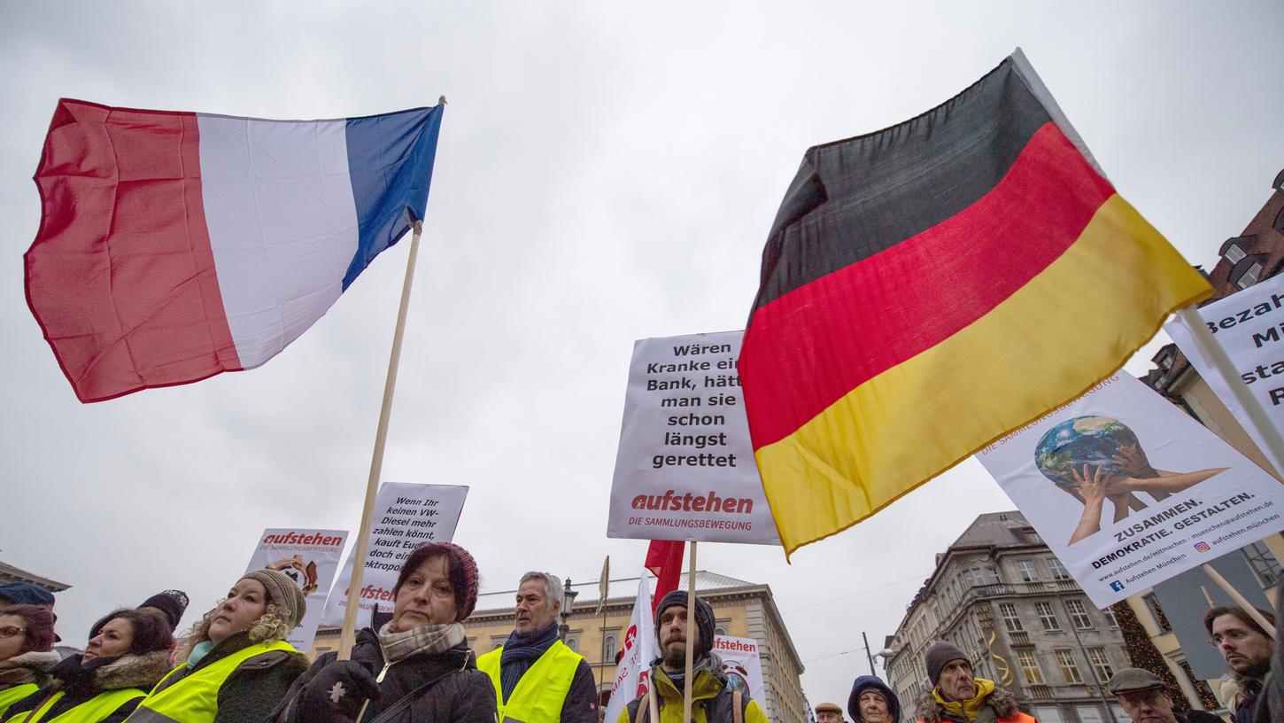 Demonstranten in Gelben Warnwesten und mit einer französischen und einer deutschen Fahne stehen bei einer Kundgebung in der Münchner Innenstadt. Die Kundgebungsteilnehmer riefen zur Solidarität mit den französischen Gelbwesten auf.