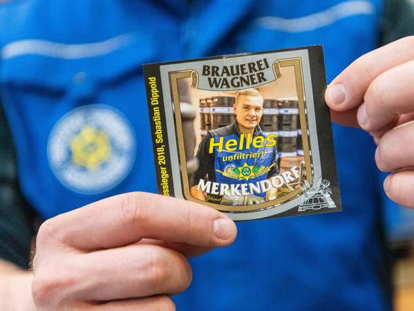 Sebastian Dippold zeigt im Lager der Brauerei Wagner das Etikett, welches sein Bundessieger-Bier tragen wird.