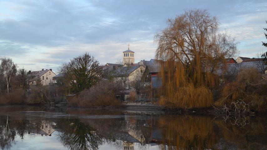 Eines der bekanntesten Gebäude des Ortes ist die Hemhofener Kirche Maria Königin, die sich hier im Wasser eines Weihers spiegelt.