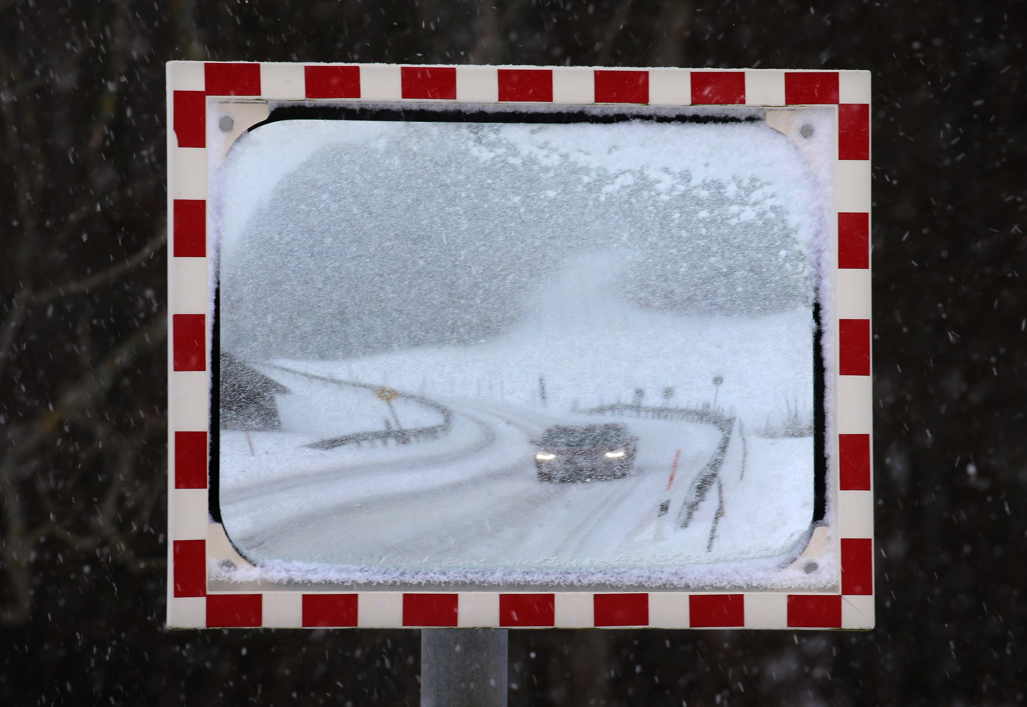 Die Schneemassen haben auch das Ostallgäu erreicht: Ein Auto fährt über eine eingeschneite Straße im Luftkurort Nesselwang am Rande der Allgäuer Alpen.