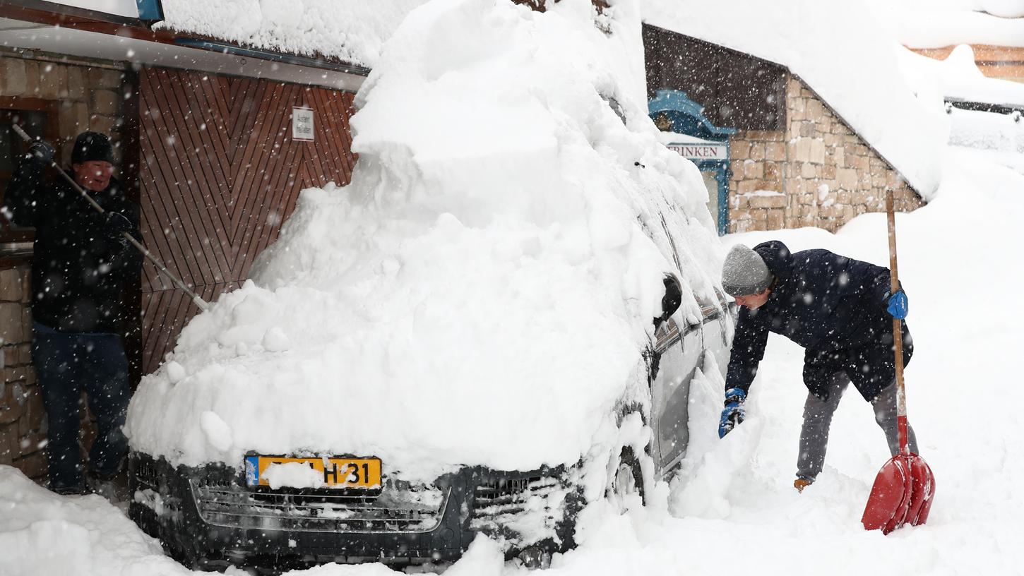 Die Weihnachtsferien sind vorbei und viele Urlauber wollen einfach nur nach Hause, doch die Schneemassen in den Bergen machen den Touristen einen Strich durch die Rechnung. Hier versuchen zwei Männer im Salzburger Land ein Auto vom Schnee zu befreien.