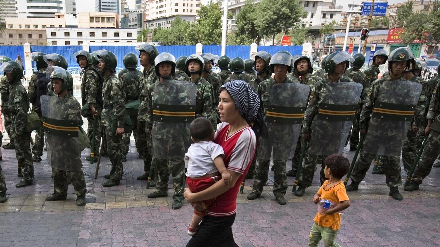 Die Lage in der Provinz Xinjiang eskaliert immer wieder: 2009 schossen chinesische Sicherheitskräfte auf aufständische Uiguren. Eine uigurische Mutter passiert hier eine der aus dem Vorfall resultierenden Straßenpatrouillen in der Stadt Ürümqi.