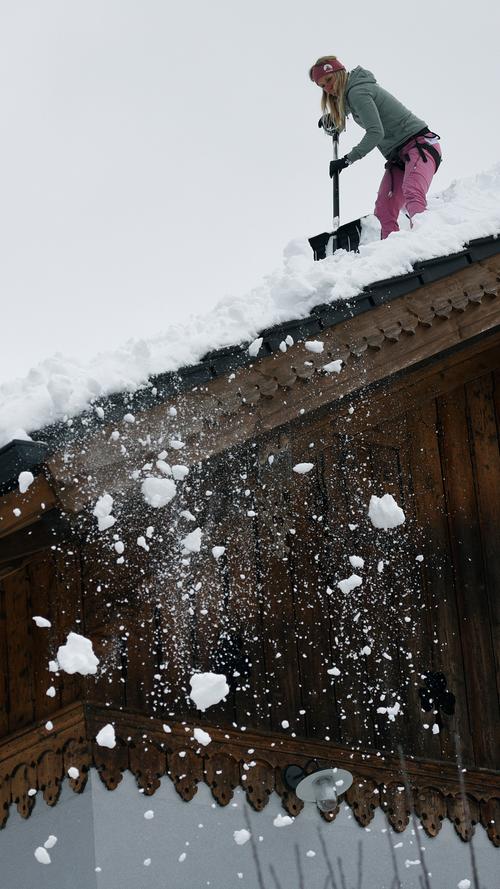 Eine Frau befreit in Garmisch-Partenkirchen ihr Hausdach von der Schneelast.