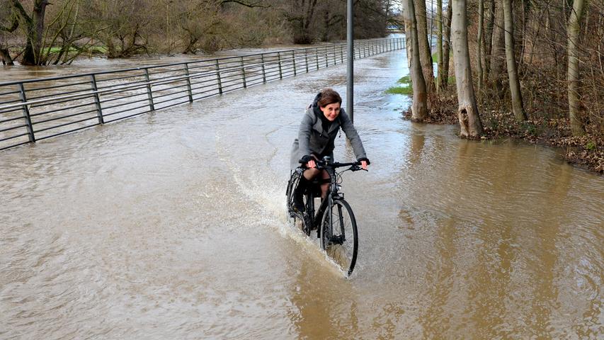 Das Hochwasser an der Fürther Uferpromenade hielt diese Radfahrerin nicht auf.