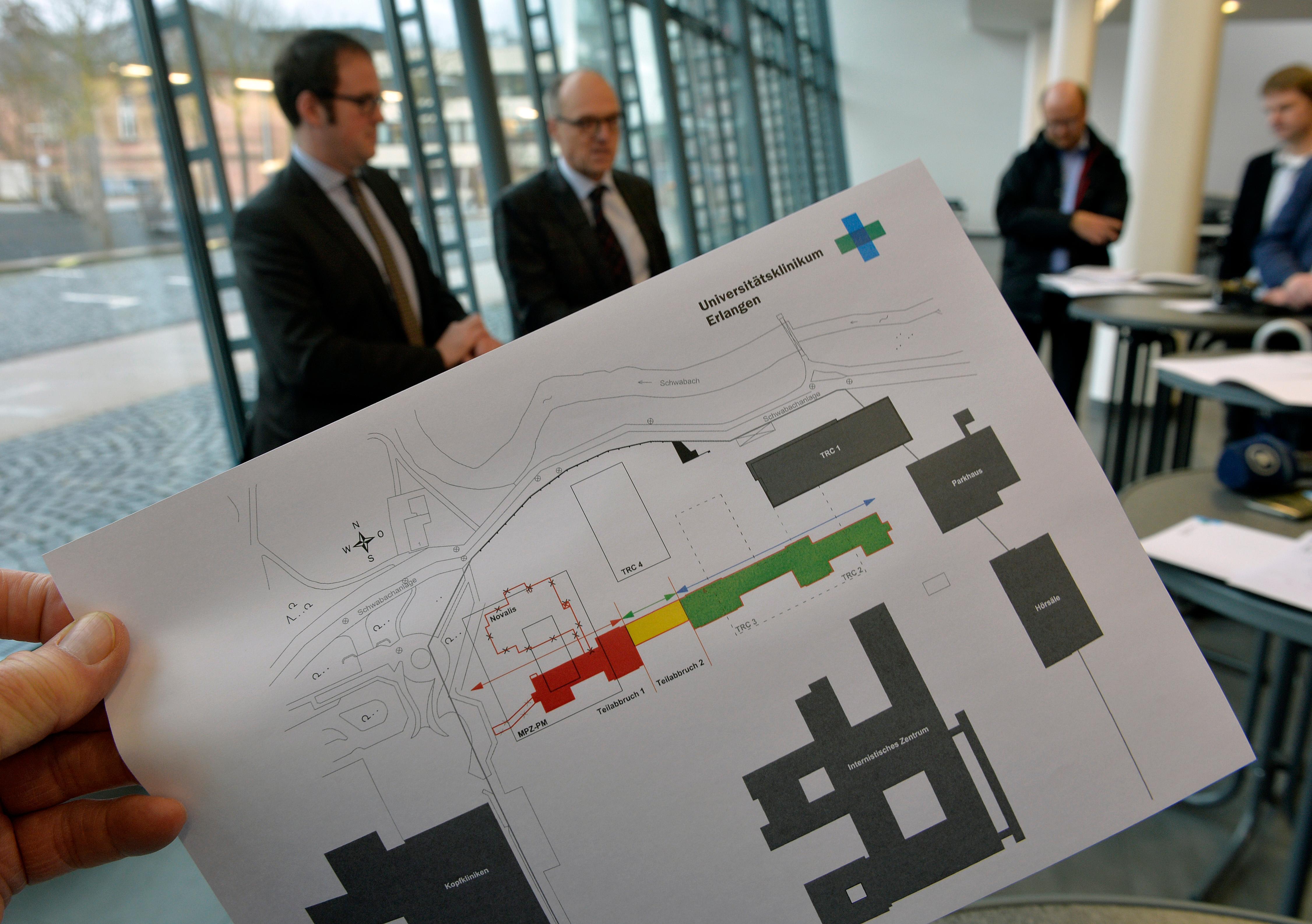  Im Zuge der Ausweitung des TRC und um Platz für den Bau eines Max-Planck-Zentrums zu machen, soll der sogenannte "Hupfla"-Kopfbau  zum größten Teil abgerissen werden. Der Plan im Vordergrund zeigt das Kopfgebäude mit Bauphasen, dahinter OB Florian Janik und Heinrich Iro, Ärztlicher Direktor der Universitätskliniken.