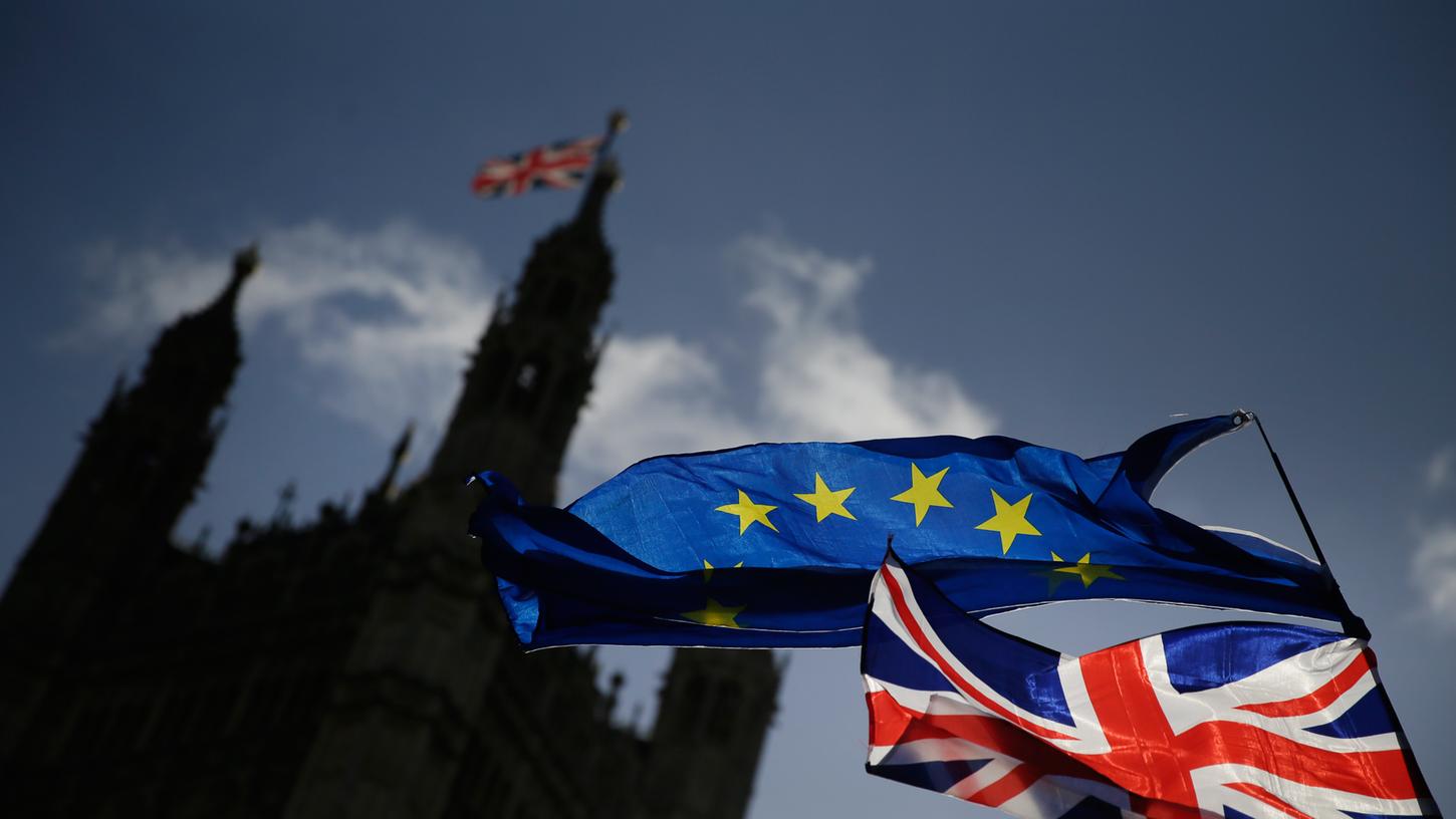 Eine EU-Flagge und eine britische Nationalflagge wehen während einer Demonstration vor dem britischen Parlament im Palace of Westminster. Am 29. Januar sollen die Abgeordneten entscheiden, wie es mit dem EU-Austritt weitergeht.