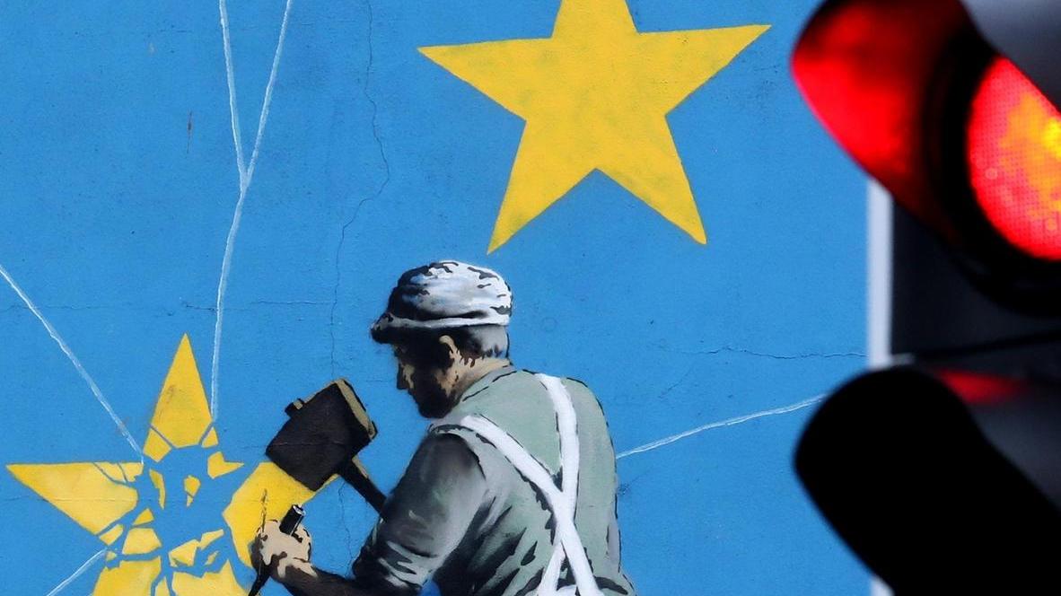 Das bereits berühmte Brexit-Wandbild des unbekannten Streetart-Künstlers Banksy in Dover zeigt einen Mann, der die EU-Flagge mit einem Hammer entfernt. Foto: Gareth Fuller/PA Wire/dpa