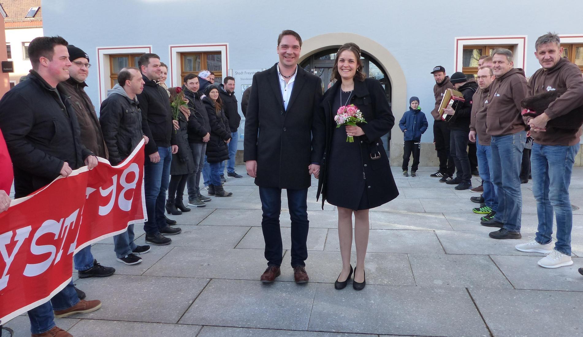 Auf dem Rathausvorplatz im Freystadt wimmelte es nur so von Gratulanten, die die Frischvermählten Tanja Feierler aus dem Freystädter Ortsteil Rohr und Klaus Schmid aus Freystadt bei ihren ersten Schritten ins Eheglück begleiten wollten. Die Freystädter Bärentreiber, bei denen der Bräutigam aktiv mittut, waren mit ihrem Quetschnspieler da, der das Paar bei seinem Defilee von der Rathaustür durch das Spalier musikalisch begleitete, die Freunde vom FC Bayern-Fanclub Freystadt, die Fußballer vom TSV Freystadt und jede Menge Freunde und Nachbarn von der Straße "Am Stadtgraben", wo beide wohnen. Sie hatten einen Sektempfang vorbereitet, bei dem sie die Liebenden hochleben ließen. Zuvor hatte Standesbeamter Martin Harrer die Trauung im Beisein der Familien vorgenommen. Zur Hochzeitsfeier luden die 29-jährige Einzelhandelskauffrau und der 32-jährige Maschinenverkäufer im Außendienst ins Sportheim der DJK Rohr. Beide sind seit knapp drei Jahren zusammen und freuen sich auf ihr Baby, das im März zur Welt kommen wird. Hier geht es zu allen Hochzeiten des Jahres 2018