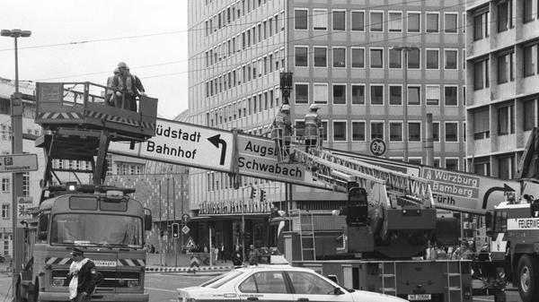 Ups, schon war es passiert: Ein Reparaturtrupp musste in den 1990er-Jahren an den Plärrer ausrücken, weil ein Lastwagen eine Schilderbrücke gerammt hatte. Links im Bild: Ein damals fast schon historischer Turmwagen mit ausfahrbarer Arbeitsbühne. Es handelt sich um einen Mercedes-Benz LP, die Baureihe stammt aus den 1960er- und 1970er-Jahren. Die Nürnberger Polizei fuhr damals die dritte Baureihe des 3er-BMWs, die sich heute gerade aus dem täglichen Straßenbild verabschiedet.