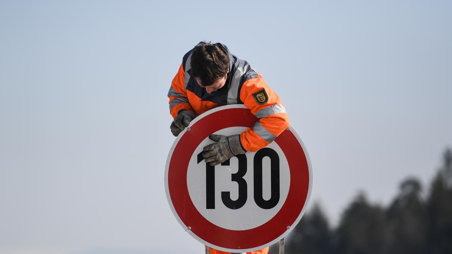 Ein Straßenwärter montiert an der Autobahn A81 am Hegaublick ein Schild mit der Aufschrift "130".