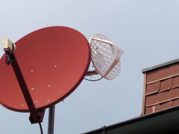 Wie eine kleine Satellitenschüssel: Die weiße Richtfunkantenne auf Steffen Winklers Hausdach ist mit einem Ausleger am Mast der Satellitenantenne.