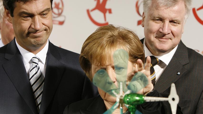 Natürlich trafen sich hier auch Parteifreunde, aber glücklich sieht anders aus. Das Foto, das Bundeskanzlerin Angela Merkel 2009 bei ihrem Besuch auf der Spielwarenmesse mit Ministerpräsident Horst Seehofer und Ministerpräsidenten-Anwärter Markus Söder (li.) zeigt, hat definitiv visionärem Charakter - auch in Bezug auf das Spielzeug-Windrad: Zwei Jahre später leitete die Kanzlerin nach dem Raktorunglück in Fukushima die Energiewende ein.