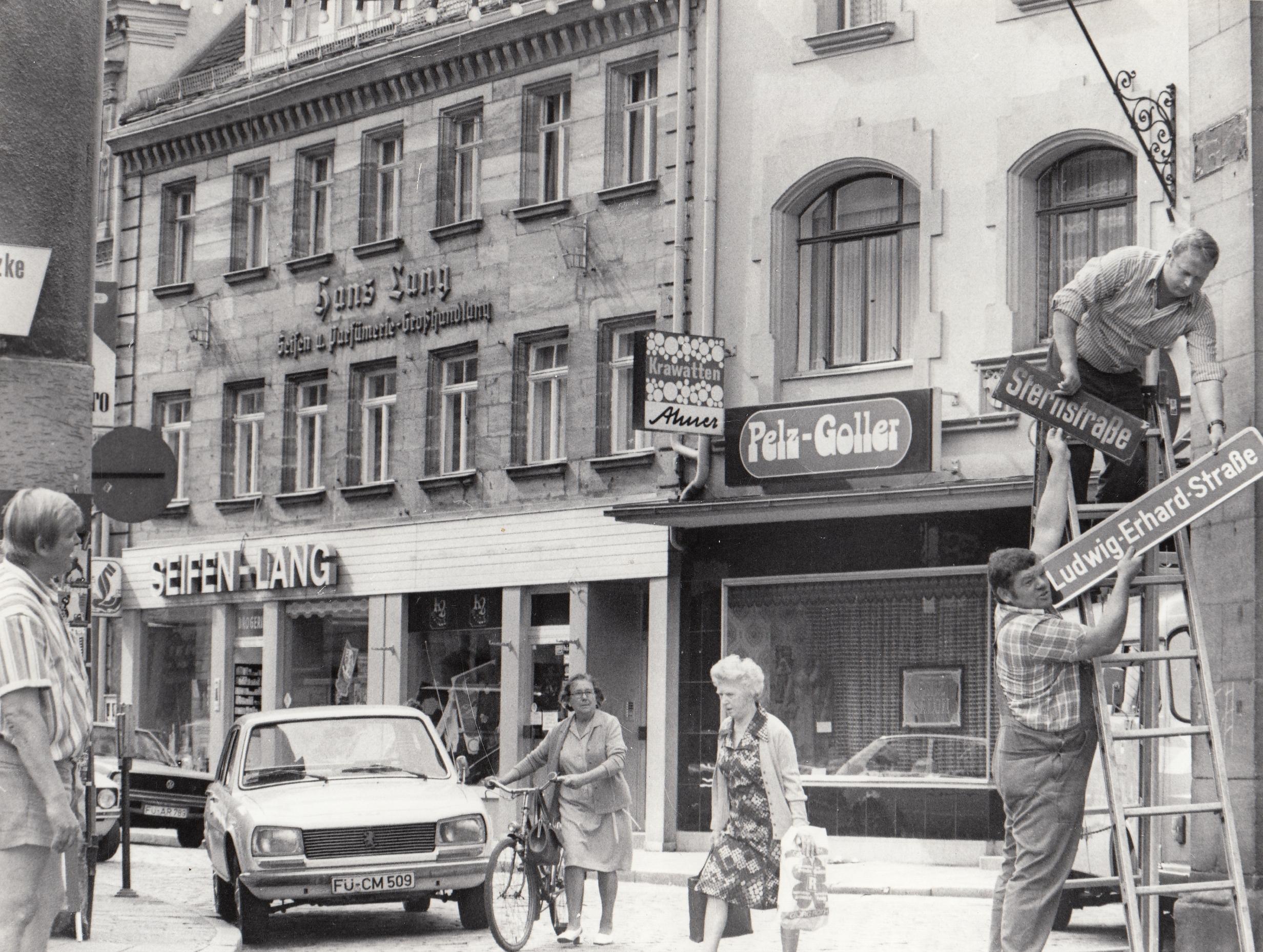 16 Wochen nach dem Tod von Ludwig Erhard erhielt der Vater des deutschen Wirtschaftswunders und Ex-Bundeskanzler anno 1977 in seiner Heimatstadt eine offizielle Ehrung: Die Schilder der Sternstraße wurden gegen neue, vom Stadtrat Mitte Juni beschlossene Schilder mit dem Namen Ludwig-Erhard-Straße ausgetauscht. Der am Straßenrand geparkte Peugeot 504 nimmt es mit automobilem Gleichmut hin.