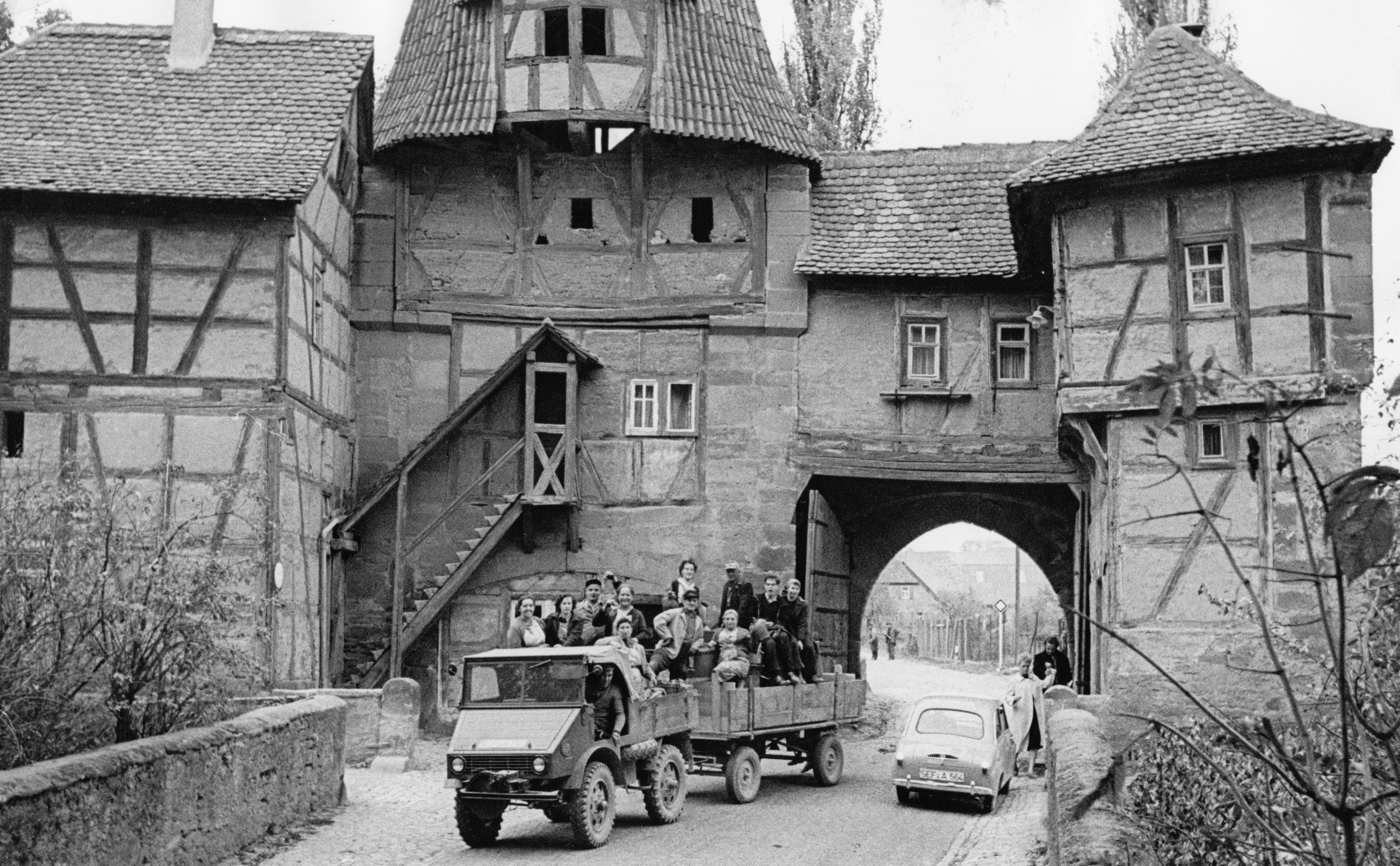 In den fränkischen Weindörfern ging im Oktober 1959 eine "Jahrhundertweinlese" zu Ende. Hier quetscht sich ein Gespann mit Erntehelfern an einem Goggomobil vorbei durch das malerische Rödelseer Tor in Iphofen. Der Weinort lag damals im mittelfränkischen Altlandkreis Scheinfeld (SEF) und gehört heute zum Landkreis Kitzingen (KT) in Unterfranken.
