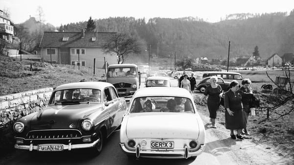 Damals, als Ford und Opel noch Autos der oberen Mittelklasse bauten... Vorne im Bild kommen sich gerade ein Ford Taunus 17m - Spitzname "Badewanne" - und ein Opel Kapitän (der ab 1964 sogar den Aufstieg in die automobile Oberklasse schaffte) entgegen. Der Lieferwagen links im Hintergrund ist ein damals schon rarer Faun F24. Wanderer hatten es an den Osterfeiertagen anno 1962 übrigens nicht ganz leicht: Oft wurden sie - wie hier bei Behringersmühle in der Fränkischen Schweiz - hart an den Straßenrand gedrängt und mit Staub bedeckt.
