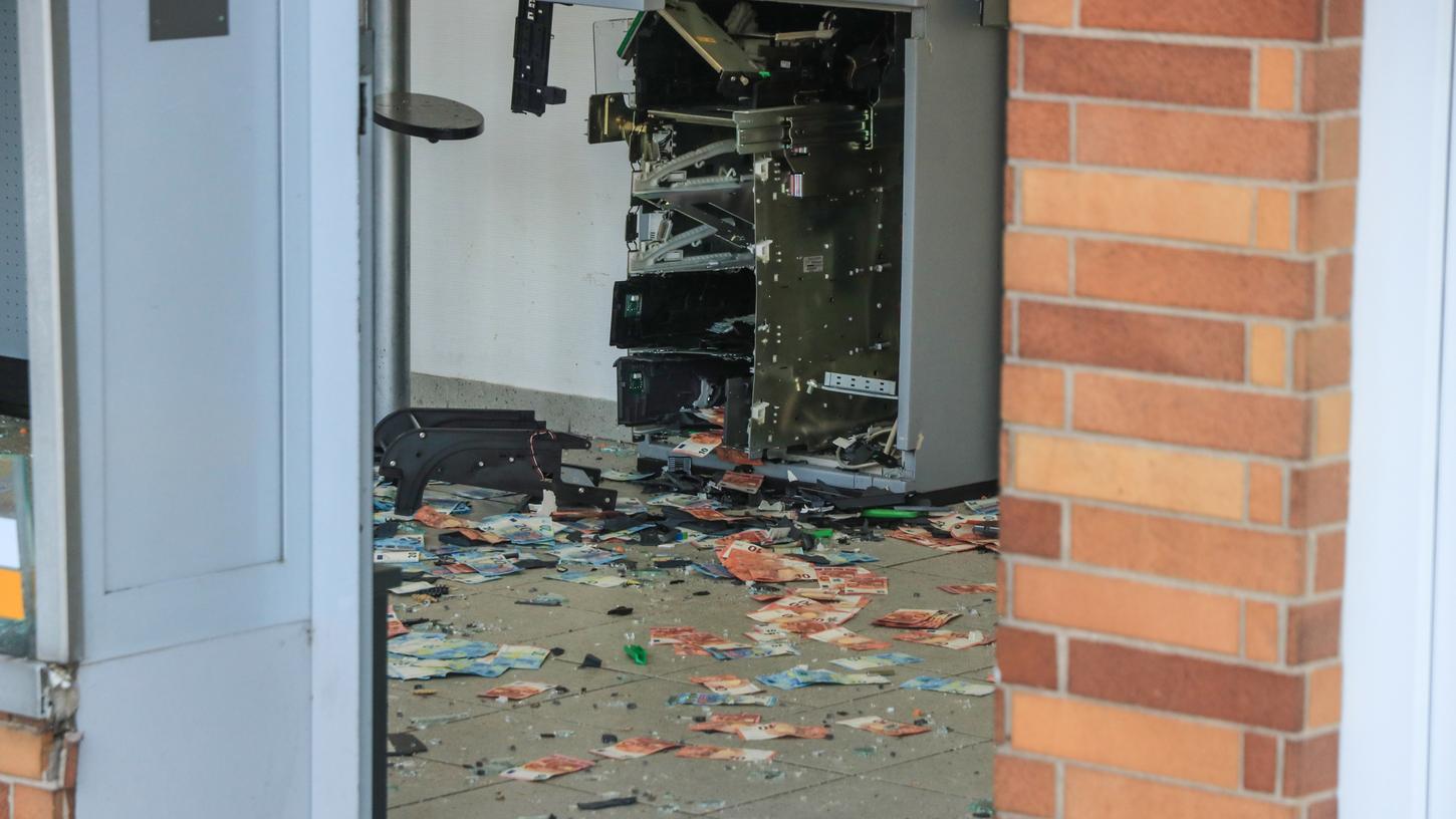 Geldscheine liegen zwischen Glas- und Plastiksplittern auf dem Boden: Nach der Sprengung eines Geldautomaten in Bamberg sichert die Polizei die Spuren vor Ort.