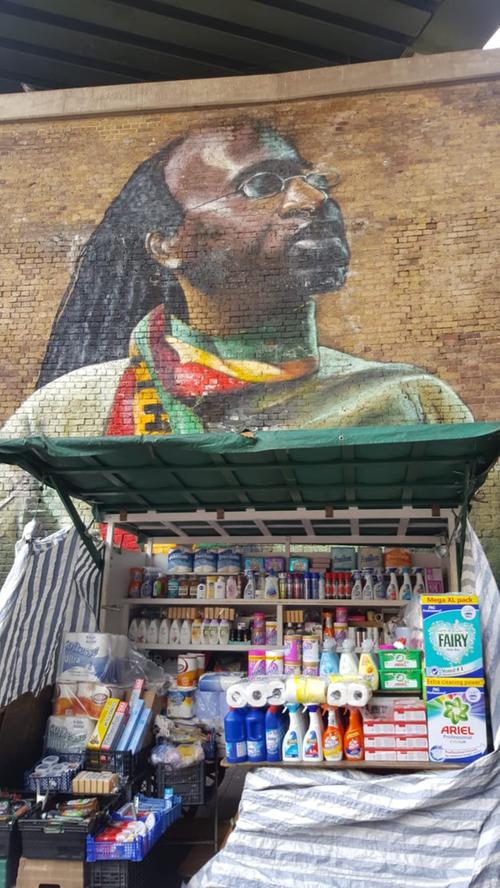 Ein riesiges Wandgemälde eines Rastfaris ziert die Wand hinter einem Verkaufsstand in Brixton.