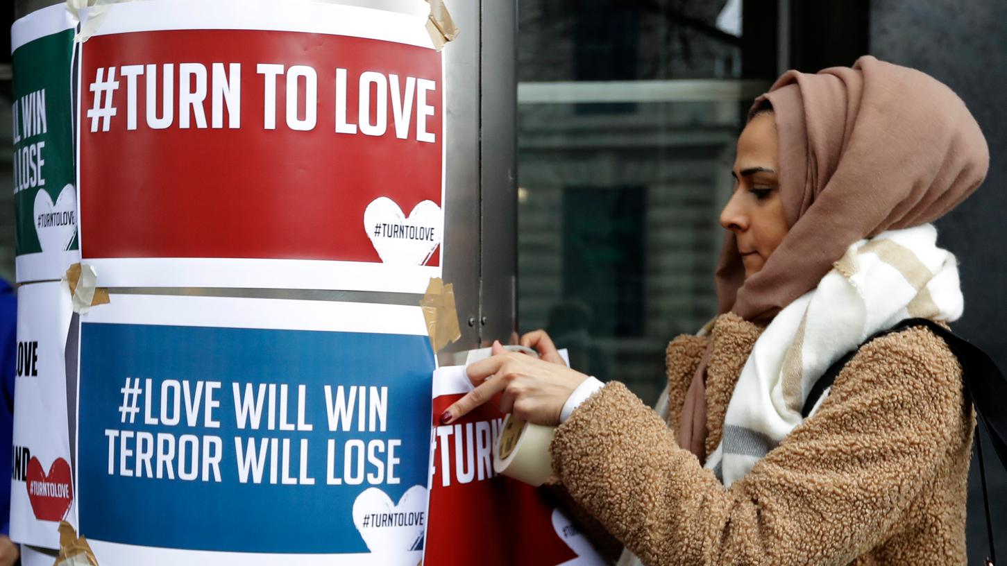 Nachdem ein mutmaßlicher Australier an zwei Moscheen in Neuseeland 49 Menschen tötete, finden nun weltweit Kondolenztreffen statt. Hier befestigt eine Frau Plakate an der neuseeländischen Botschaft und wirbt für mehr Liebe statt Hass.