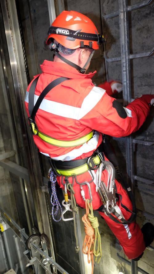 Um zu eingeschlossenen Personen zu gelangen, muss Höhenretter Roland Scherzer zunächst den Aufzugschacht hinunterklettern.