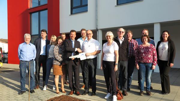 Schlüsselübergabe an die künftigen Eigentümer und Bewohner mit Projektentwickler Helmut Stranzinger und dem stellvertretenden Rotkreuz-Kreisgeschäftsführer Martin Fickert (Mitte, mit symbolischem Riesenschlüssel).