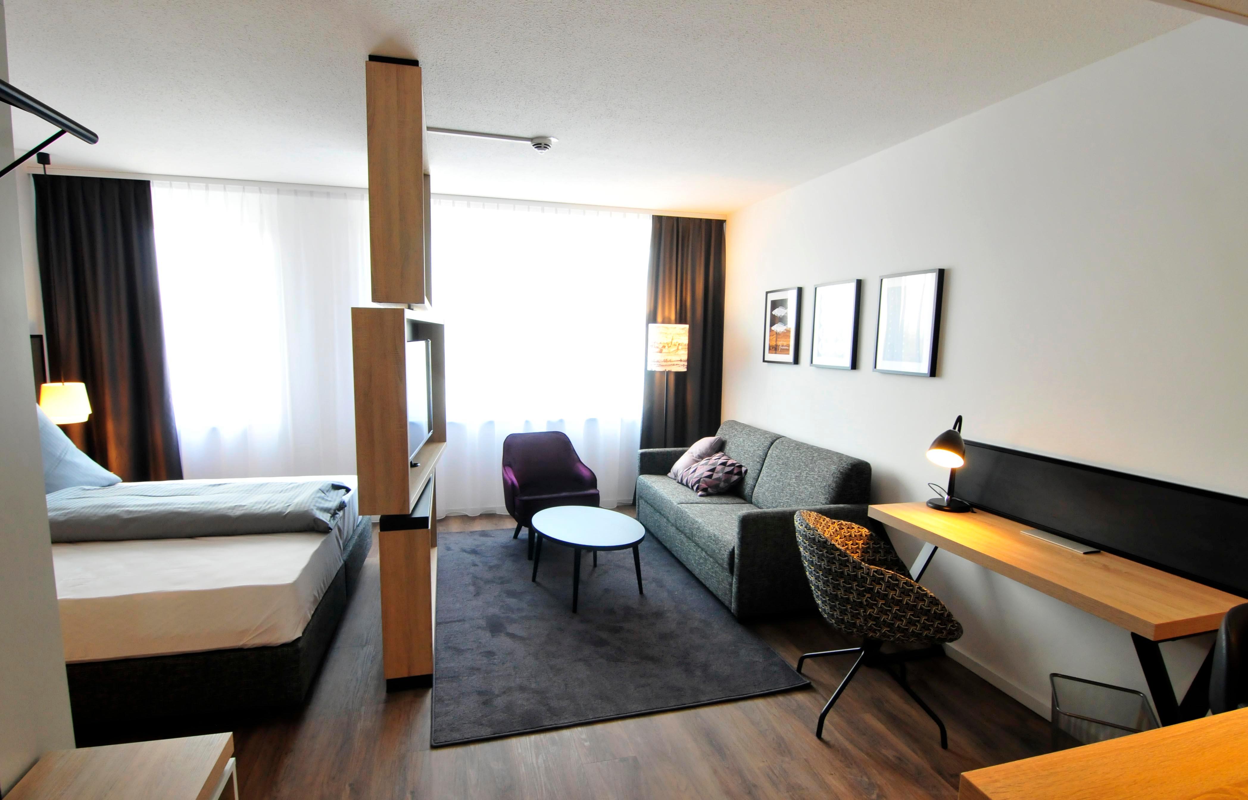 Blick ins Standard-Appartement für Langzeitaufenthalte. Mit Küchenzeile, Schreibtisch (inklusive Highspeed-Internet) und schwenkbarem TV-Gerät.