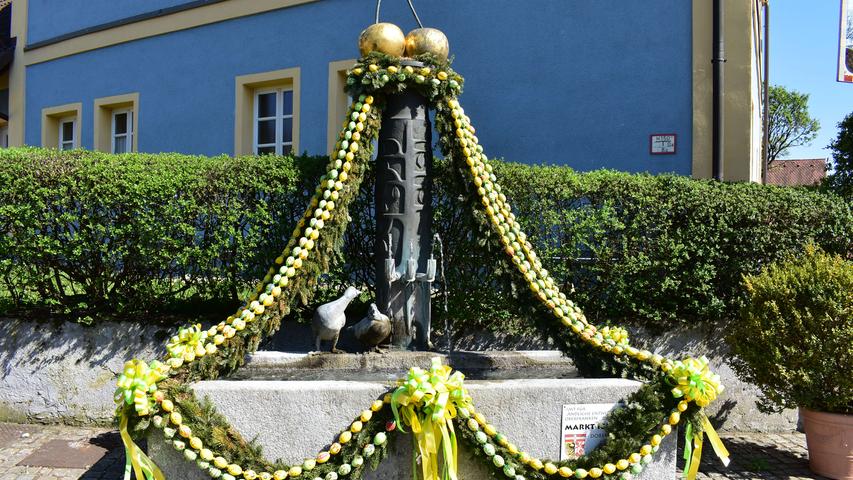 Ein weiterer Osterbrunnen in Igensdorf steht vor dem ehemaligen Schulhaus und erstrahlt in fröhlichen Frühlingsfarben.