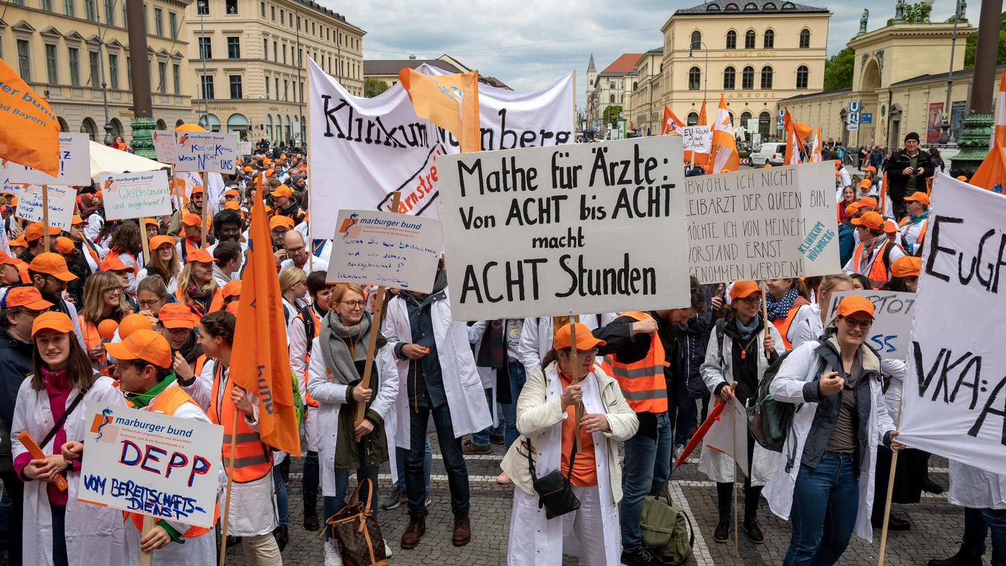 Teilnehmer der Kundgebung der bayerischen Klinikärzte stehen mit Plakaten auf dem Odeonsplatz.