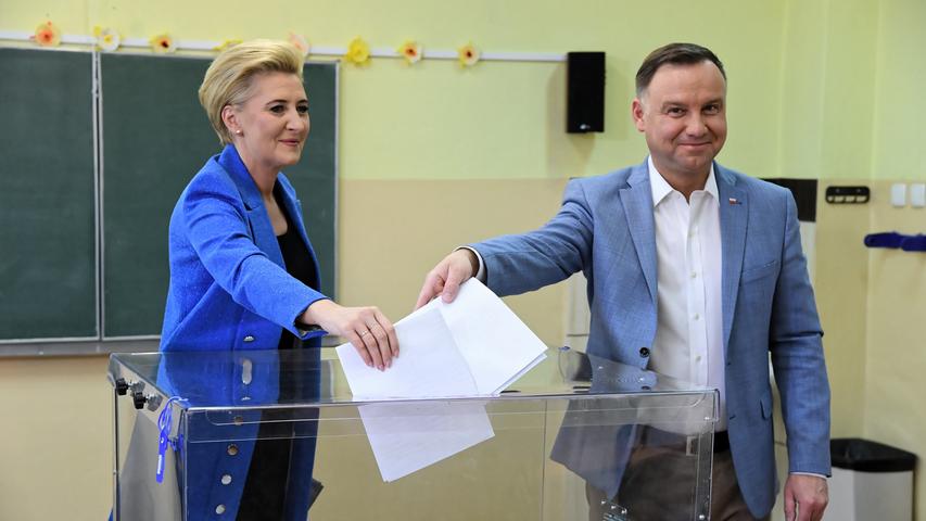 Andrzej Duda, Präsident von Polen, und seine Frau Agata Kornhauser-Duda werfen ihre Stimmzettel für die Europawahl in Krakau eine Wahlurne.