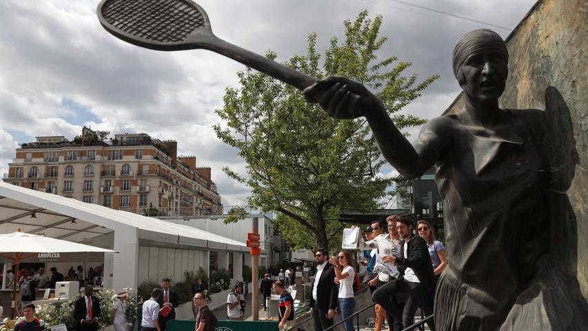 Paris:   Zuschauer der dritten Runde der French Open gehen an einer Statue der ehemaligen französischen Tennisspielerin Suzanne Lenglen vor dem Court vorbei.