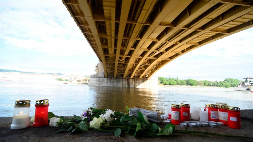 Blumen und Kerzen liegen unter einer Donaubrücke in Budapest. Etliche Menschen sind dort bei einem Schiffsunglück ums Leben gekommen.