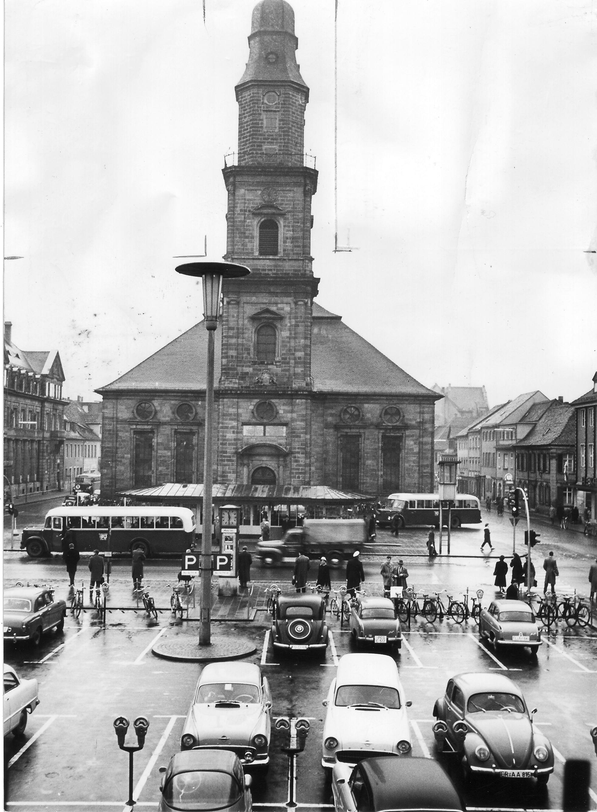 1957 sah der Hugenottenplatz in Erlangen noch völlig anders aus als heute. Damals gab es auch noch keine Fußgängerzone in der Stadt. Diese wurde erst im Dezember 1973 eingeführt, als zunächst an Samstagen die Hauptstraße für Fahrzeuge gesperrt wurde. Am 22. Mai 1976 wurden der Ostteil des Hugenottenplatzes und die Untere Karlstraße zur Fußgängerzone erklärt.
