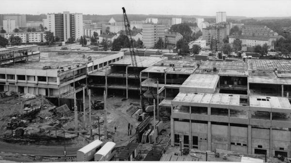 Ein Blick auf die Baustelle, auf der nach einem ausgeklügelten System mit Fertigteilen gearbeitet wird. Die zweigeschossige Anlage erhält eine überdachte, klimatisierte Ladenstraße mit einer Schaufensterfront von rund einem Kilometer. Bis in vier Monaten soll das Einkaufszentrum im Herzen des neuen Stadtteils soweit vollendet sein, daß die Geschäfte bereits ihre Pforten öffnen können und die Bewohner von Langwasser ein vielfältiges Warenangebot vorfinden werden. Das Vorhaben soll neue städtebauliche Akzente setzen. Hier geht es zum Artikel vom 14. Juni 1969: "Neues Warenhaus in der City".