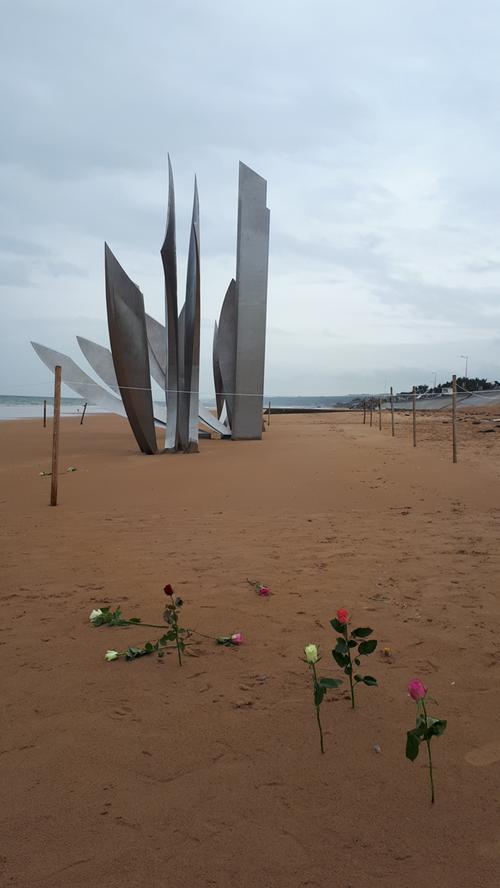 An der Skulptur "Les Braves" an Omaha Beach haben Menschen Rosen in den Sand gesteckt.