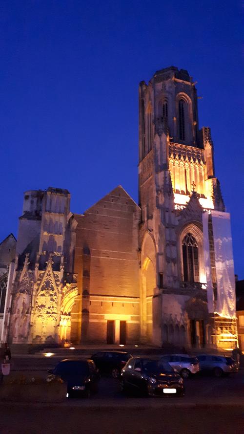 Effektvoll beleuchtet: die Fassade der Kirche Notre Dame der Provinzstadt Saint-Lo. Die Fassade des von Bomben schwer getroffenen Gotteshauses wurde nicht rekonstruiert, sondern mit einer modernen Mauer versehen, das als Narbe an die schweren Verwundungen erinnert.