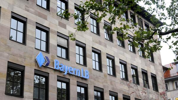 Der Nürnberger Standort der Bayerischen Landesbank liegt nicht nur direkt gegenüber der Sparkasse am Lorenzer Platz, die BayernLB gehört auch der gleichen Finanzgruppe an wie der Nachbar mit dem roten Logo: Landesbanken zählen wie die Sparkassen zum öffentlich-rechtlichen Sektor. Die genossenschaftlichen sowie die privaten Banken bilden weitere zwei der zusammen drei Säulen des deutschen Finanzsystems. Die Bayern LB hat ihren Hauptsitz in München. In Nürnberg betreibt die Bank ihr Kompetenzzentrum für Sorten und Edelmetalle.