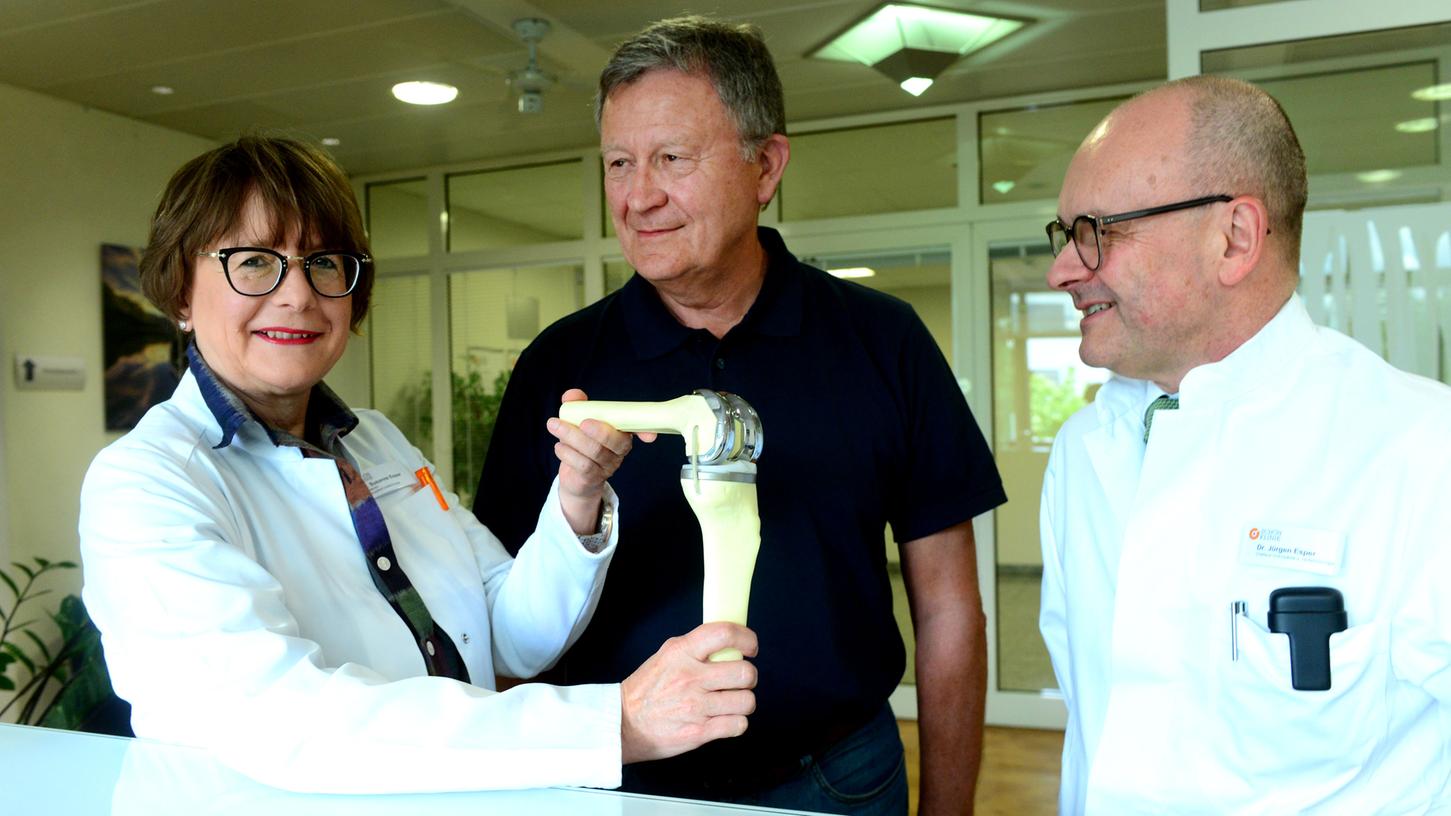 Dr. Susanne Esper und Dr. Jürgen Esper (r.), Orthopädie-Chefärzte an der Fürther Schön-Klinik, zeigen das Modell einer Knieprothese. Ex-Patient Werner Rupp ist mit dem Ergebnis zufrieden.