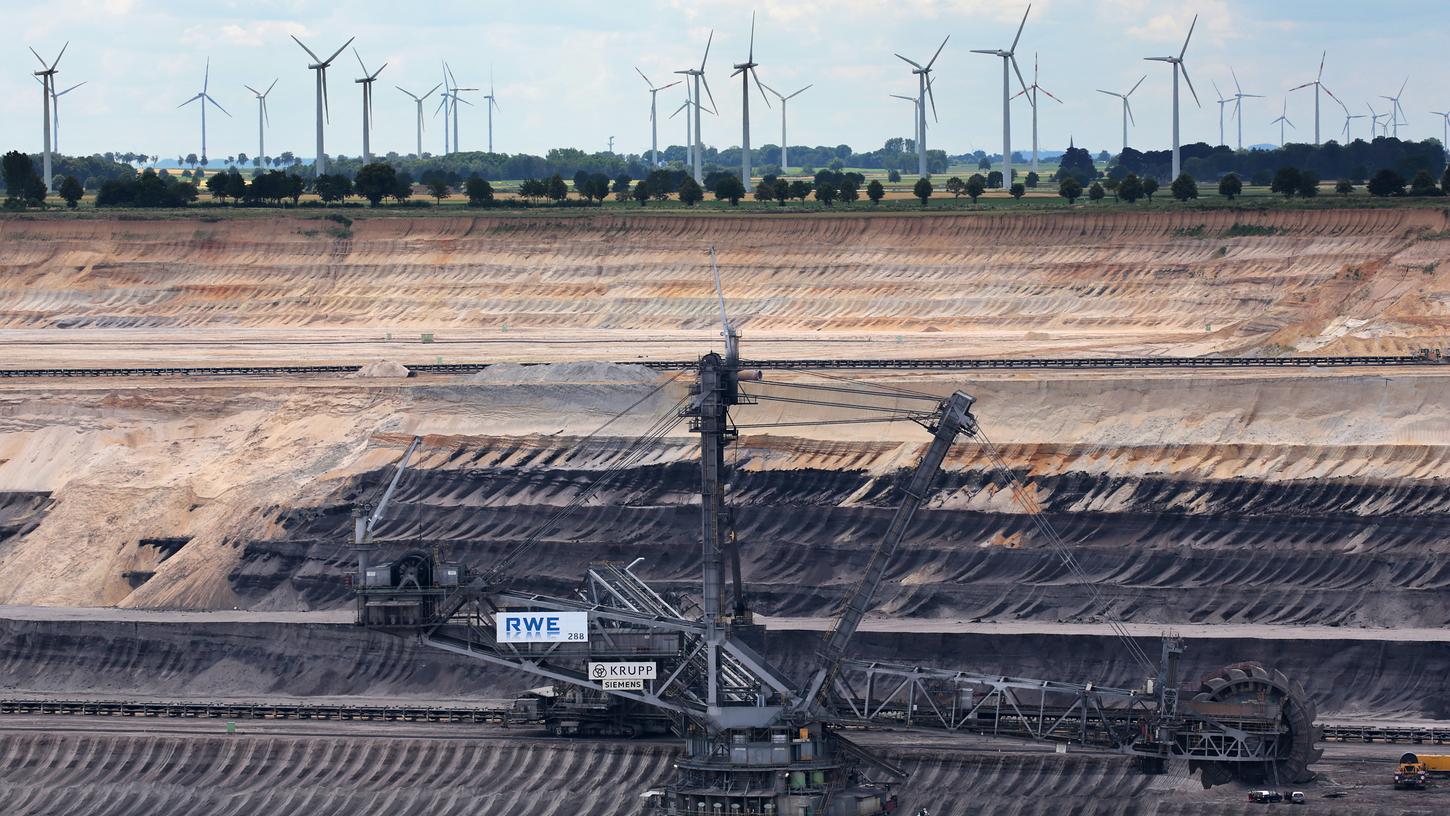 Energiewende auf einem Bild: Ein Braunkohlebagger im Tagebau Garzweiler (Nordrhein-Westfalen), dahinter drehen sich die Windräder.