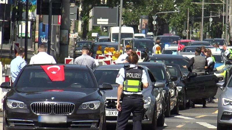 Eine Polizistin steht vor den Fahrzeugen eines türkischen Hochzeutskorsos. Der Konvoi hatte in Köln für Aufregung gesorgt.